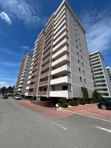 a tall apartment building with cars parked in a parking lot at Blue Apartment with Free Parking&Self Check-in in Bistriţa