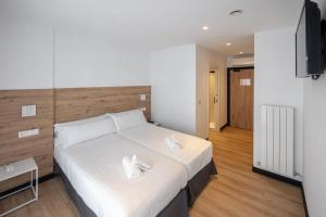 a bedroom with a bed with two white shoes on it at Donosti rooms in Loyola