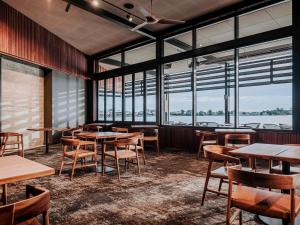 a restaurant with tables and chairs and large windows at The Sebel Yarrawonga Silverwoods in Yarrawonga