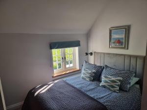 a bedroom with a bed with pillows and a window at Rose Cottage in Burnham Thorpe