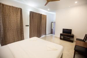 ein Schlafzimmer mit einem weißen Bett und einem Fernseher in der Unterkunft The Nest Bettathur, Coorg in Madikeri