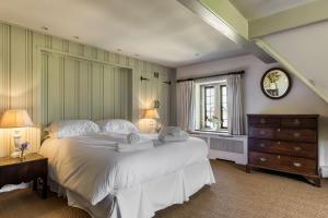 a bedroom with a large white bed and a window at Apple Cottage in Snowshill
