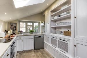 a kitchen with white cabinets and a skylight at Apple Cottage in Snowshill