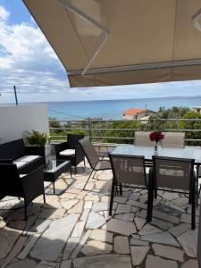 a patio with tables and chairs and a view of the ocean at Olive tree villa in Ligia