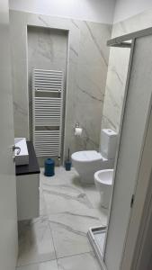 a white bathroom with a toilet and a sink at Casa Narciso, semi-detached cottage in Marina di Massa