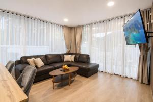 a living room with a black couch and a tv at Sunset Pool Villa Ao Nang Krabi in Ao Nang Beach