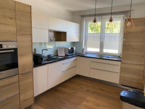 a kitchen with white cabinets and black counter tops at Pension Straßl in Andorf