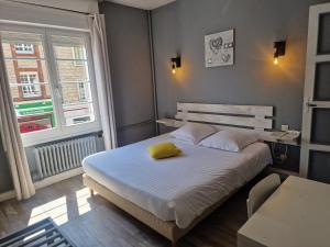 a bedroom with a bed with a yellow pillow on it at Come Inn in Neufchâtel-en-Bray