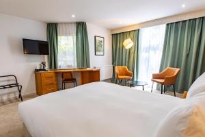 a hotel room with a large white bed and chairs at Marwell Hotel Winchester South in Winchester