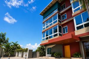 a red building with a blue sky in the background at Hotel L ! M Calangute Beach Way in Calangute