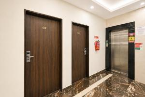two brown doors in a hallway with a fire extinguisher at Hotel L ! M Calangute Beach Way in Calangute +5 photos