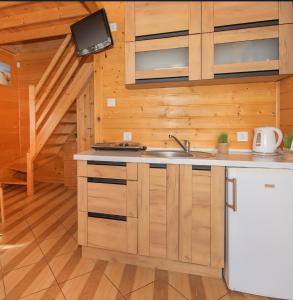 a kitchen with wooden cabinets and a sink in a cabin at Domki Maks in Bobolin
