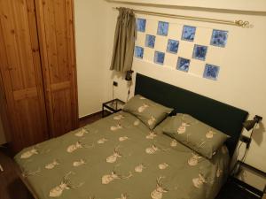 a bed with a green comforter and two pillows at Centro - La Tana di Nico & Chri in Bardonecchia