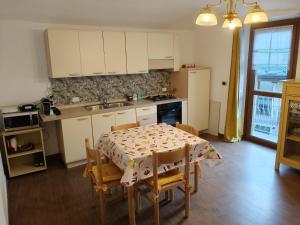 a kitchen with a table and chairs and a kitchen with white cabinets at Centro - La Tana di Nico & Chri in Bardonecchia