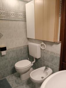 a bathroom with a white toilet and a sink at Centro - La Tana di Nico & Chri in Bardonecchia +4 photos