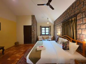 a bedroom with a large bed with a brick wall at Tiger Trails Resort in Tāla +33 photos
