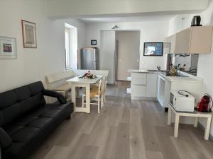 a living room with a black couch and a kitchen at Appartamento Michela in Darzo