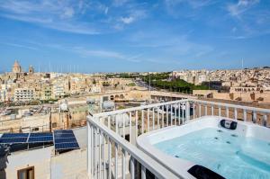a hot tub on a balcony with a view of a city at The Oasis - R4 in Senglea