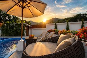 a patio with a table and an umbrella next to a pool at Sunset Pool Villa Ao Nang Krabi in Ao Nang Beach