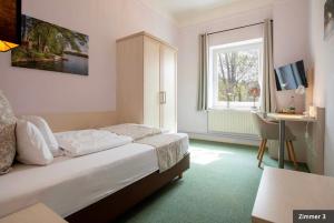 a bedroom with a bed and a desk and a window at Hotel See-Villa in Malente