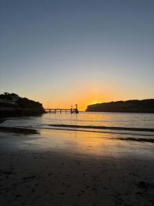 a sunset on the beach with a pier in the water at Twelve Apostles Beach House-STUDIO in Port Campbell +9 photos