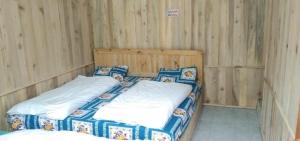 a bedroom with two beds in a wooden wall at Hotel Priyanshu in Madheso