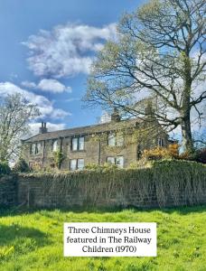 a stone house with a sign in front of it at Bents Holiday Cottage, Views & Parking for two cars in Oxenhope