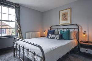 a bedroom with a bed with blue pillows and a window at Ace Cottage in Lymington