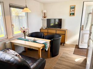 a living room with a table and chairs and a television at Ferienhäuser Vogelsang in Sagard