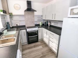 a kitchen with white cabinets and black counter tops at The Gower Gateway in Swansea