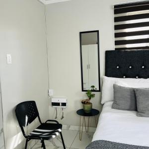 a bedroom with a bed and a chair and a mirror at 4 at Granada 1 in East London +7 photos