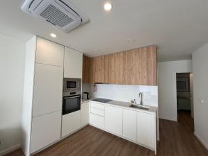a kitchen with white cabinets and a sink at O Vilarealense Heritage Apartment in Vila Real