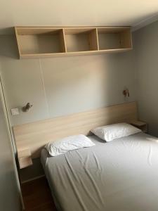a bedroom with a bed and shelves on the wall at Mobilhome Ligaropa climatisé 3 ch 6 pers camping des 7 fonts in Agde