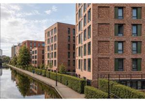 a brick building next to a river in a city at Globeworks by UTDM in Birmingham
