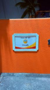 a sign on the side of a orange wall at Terra do Sol Pousada - Passarela in Porto Seguro