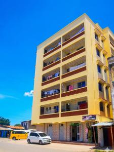 a yellow building with cars parked in front of it at Dorado Homestay, Chaani in Mombasa