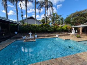 a swimming pool in a backyard with palm trees at Blue Bend Valley in East London