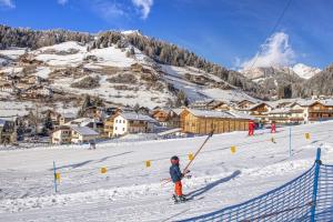 a person riding skis down a snow covered slope at Tieja Panoramic Lodge in Selva di Val Gardena