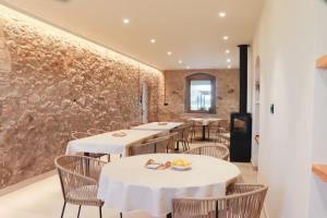 a restaurant with tables and chairs and a stone wall at Mas Les Arrabassades in Castelló d'Empúries