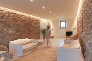 a woman standing in a living room with a stone wall at Mas Les Arrabassades in Castelló d'Empúries