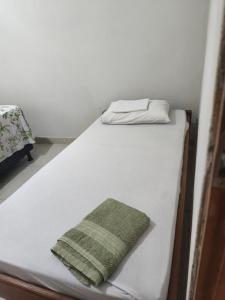 a white bed with a green pillow on it at Casa da Di in Lençóis
