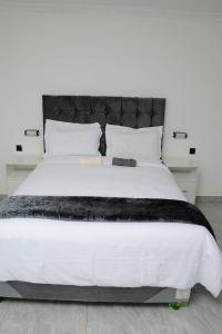 a bedroom with a large white bed with a black headboard at On Edward in Bulawayo