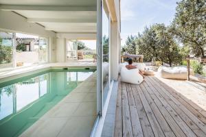 a woman sitting on the porch of a house with a swimming pool at La Villa Les Petits Gardons in Castillon-du-Gard