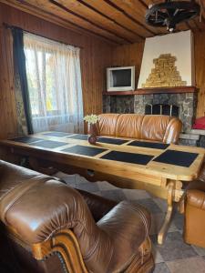 a living room with a table and a leather couch at Садиба Близнюки in Vorokhta