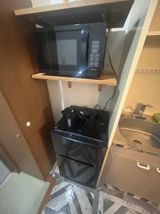a black microwave sitting on a shelf in a kitchen at 東尋坊近く自転車無料 コンビニ目の前1ルーム貸切 in Mikuni