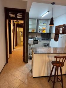a kitchen with a counter and some chairs in it at Casa Flamboyant Parajuru in Beberibe +3 photos
