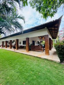 a house with a bench in the middle of a yard at Casa Flamboyant Parajuru in Beberibe