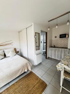 a white bedroom with a bed and a bathroom at Gîte Les Lauriers Roses in Marseillan