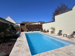 a swimming pool in a yard with chairs next to a house at Au fil de l’Ô in Bisseuil