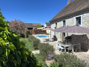 a patio with a table and an umbrella and a pool at Au fil de l’Ô in Bisseuil